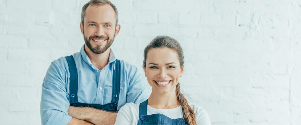 selbstbewusste Arbeiter in Overalls, die mit verschränkten Armen posieren.